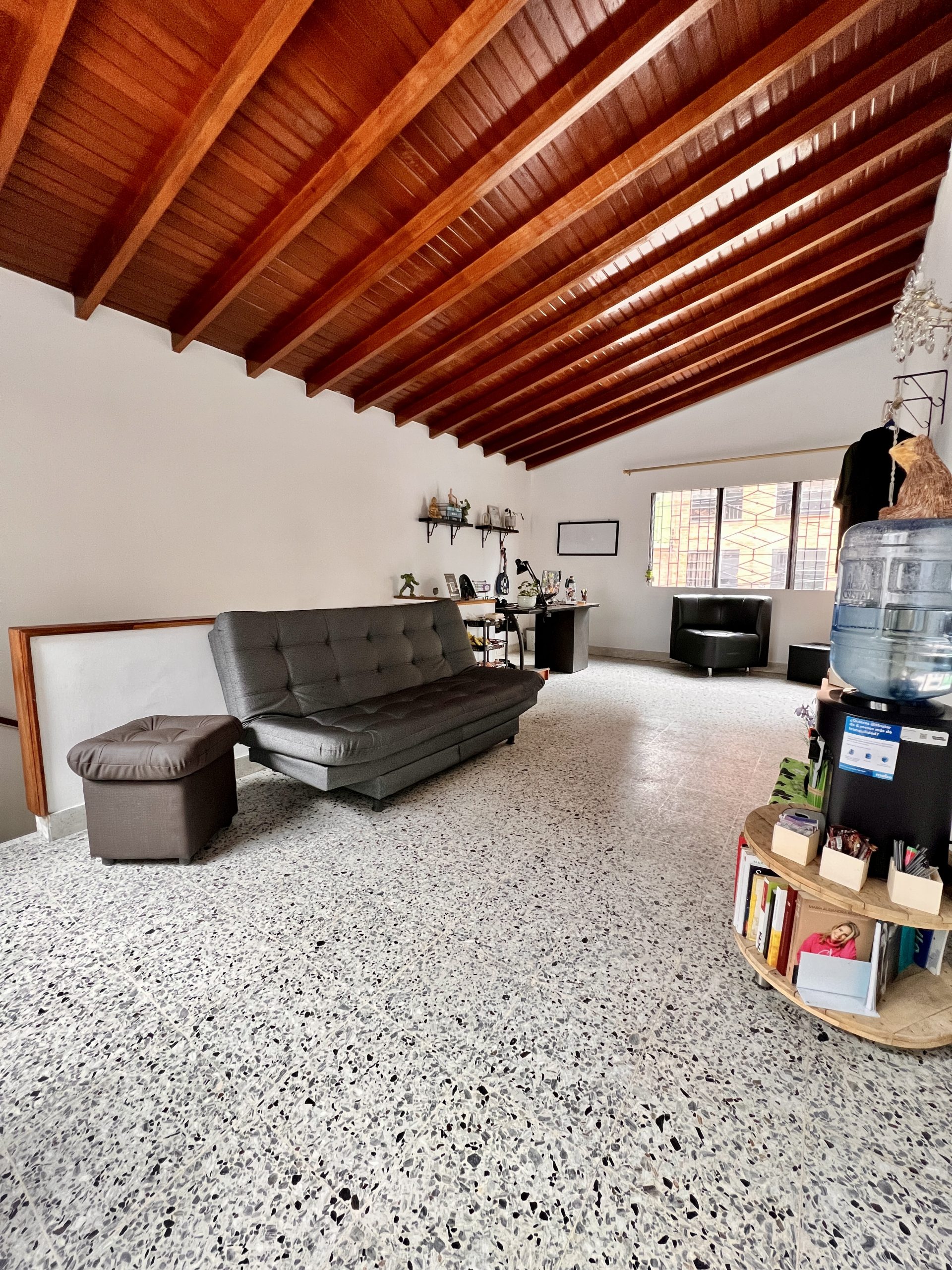 Área social del centro Mi Espacio con sofá, estación de agua y estantería con libros.